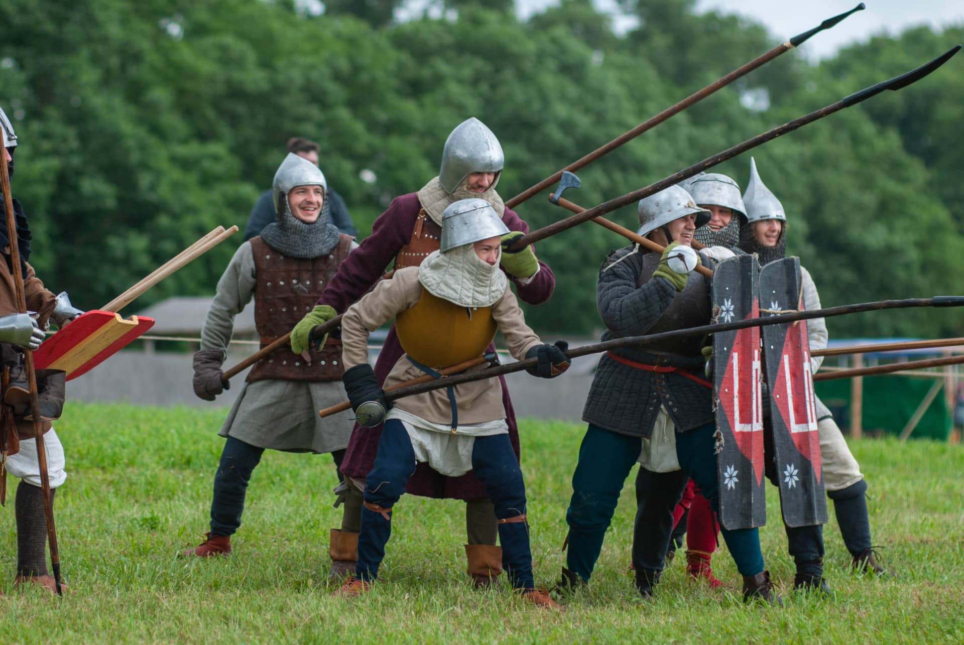 Atira Ruthenia members in helmets and gambesons advancing in a spear line at a historical festival